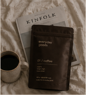 everyday goods coffee pouch, ceramic mug and Kinfolk book on an unmade bed
